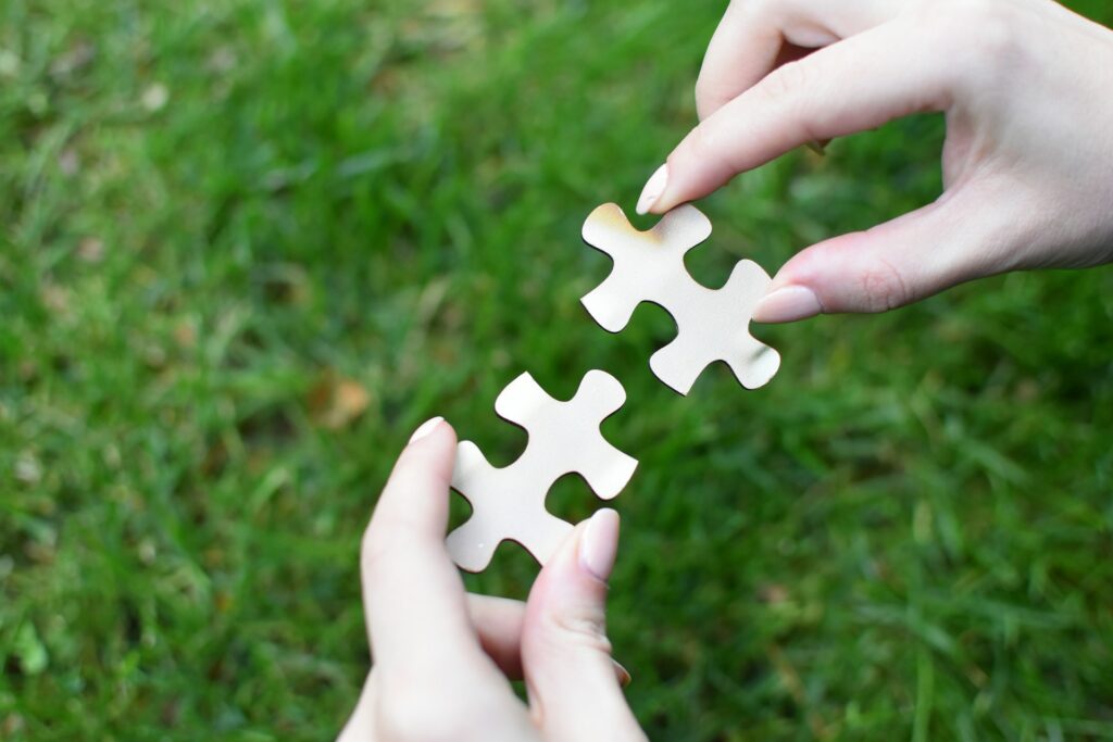 Two hands holding two puzzle pieces next to each other