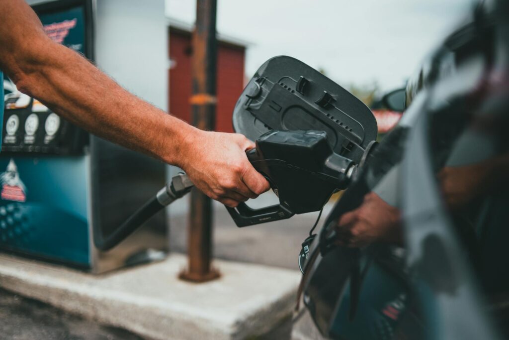 Hand holding petrol nozzle putting fuel into car